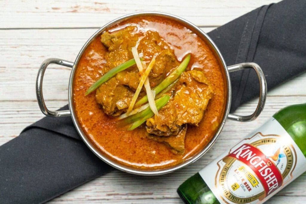 Chicken curry served in a karahi with Kingfisher beer